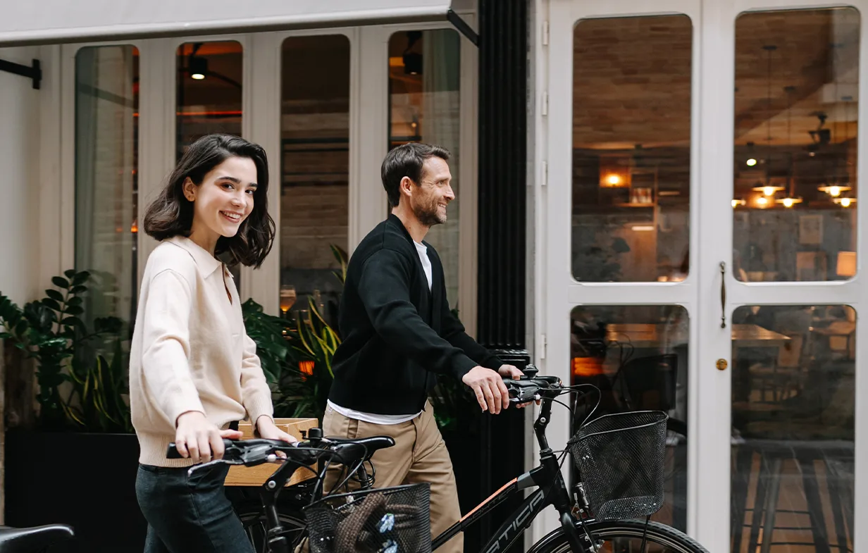 Representative hotel space: Two people stand with bicycles outside a glass-fronted entrance.