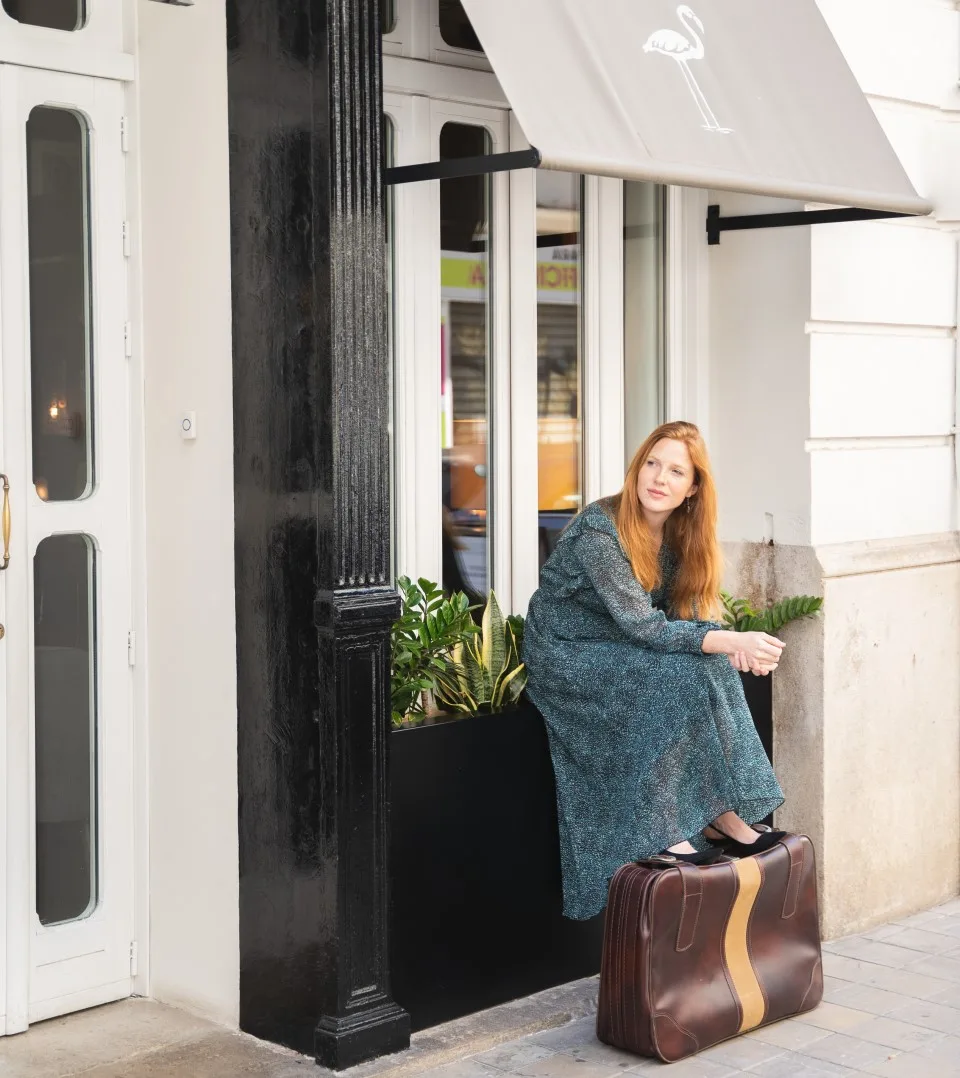Representative hotel space: A woman sits on a suitcase outside a storefront.