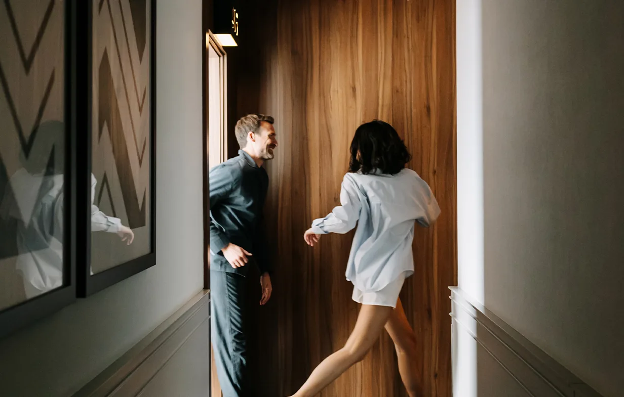 Representative hotel space: A couple stands in a narrow hallway beside a wooden door.
