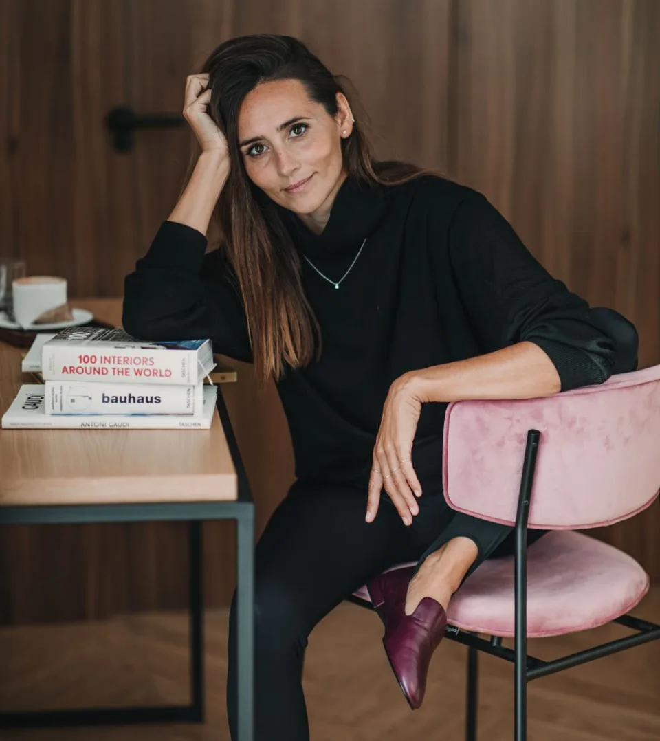 Representative hotel space: A woman sits in a pink chair beside a table with books.