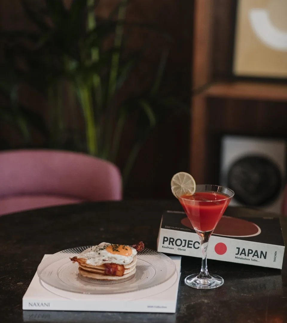 Representative hotel space: A table holds a plated dish and a red drink garnished with citrus.
