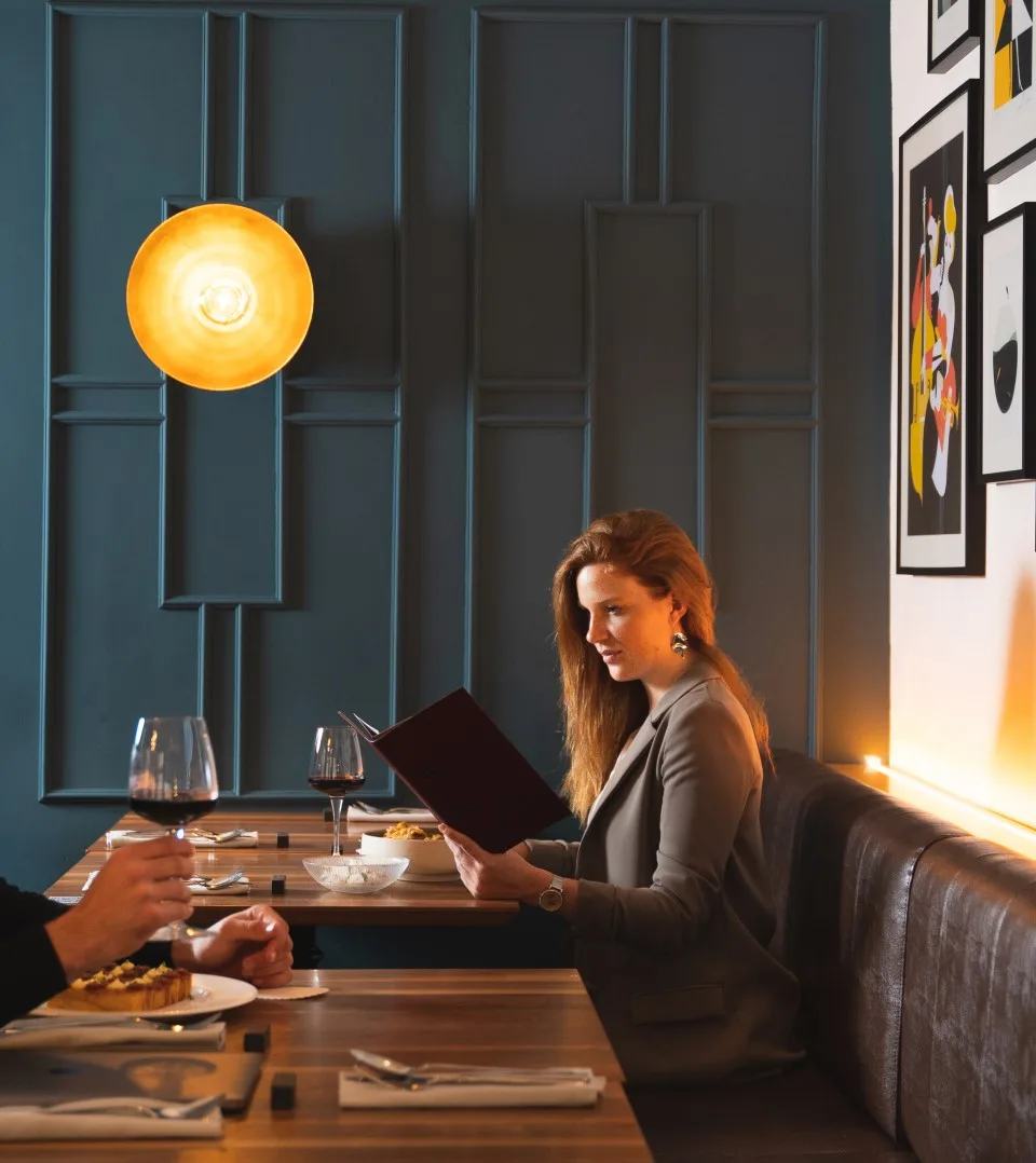 Representative hotel space: A restaurant dining area with a woman seated at a table holding a menu.