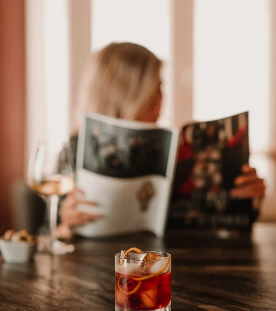 Representative hotel space: A person reads a magazine at a table beside a glass of iced drink.