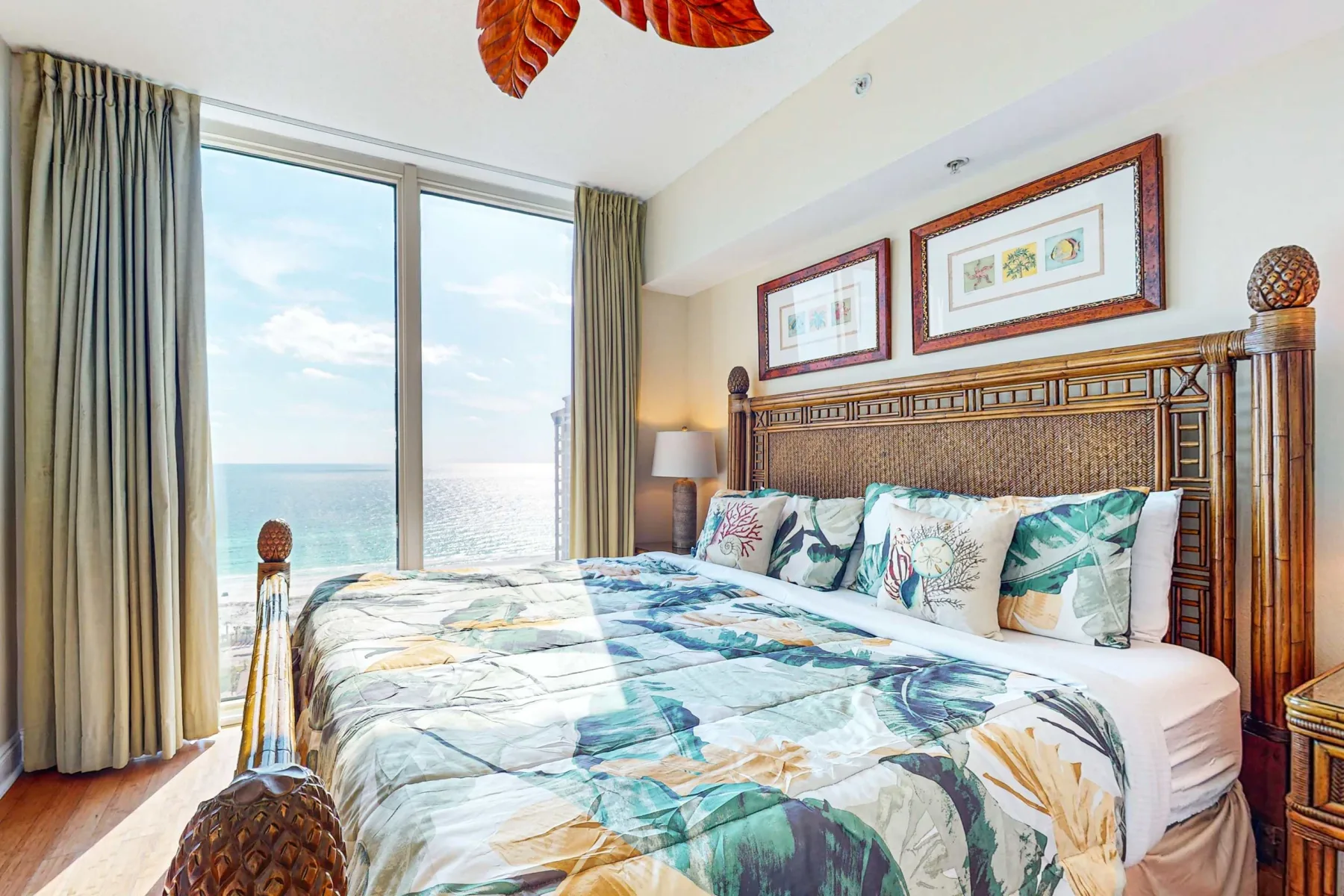 Un dormitorio con una colcha estampada junto a una gran ventana con vistas al agua.