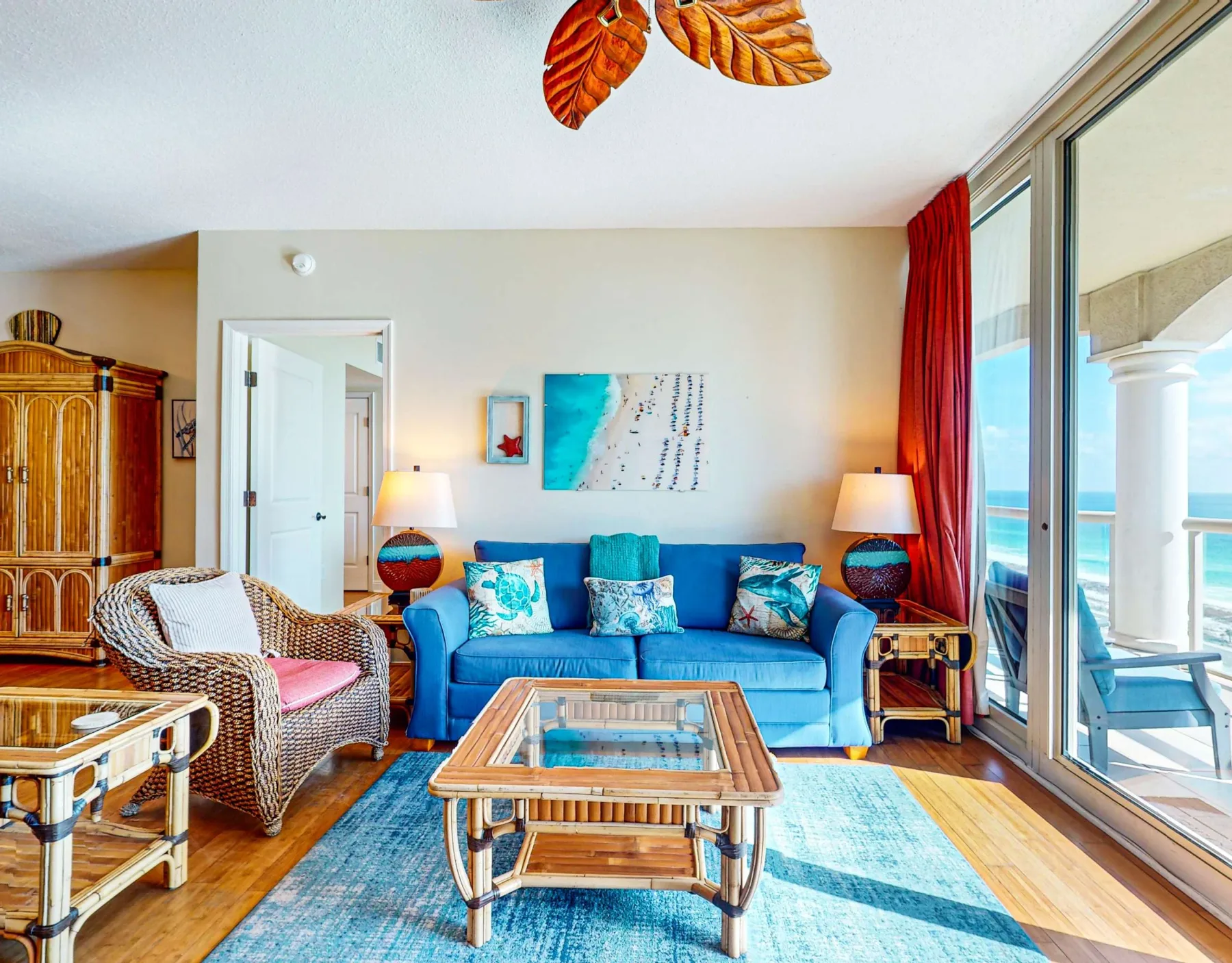 Una luminosa sala de estar con asientos azules, una mesa de centro de vidrio y vistas al mar.