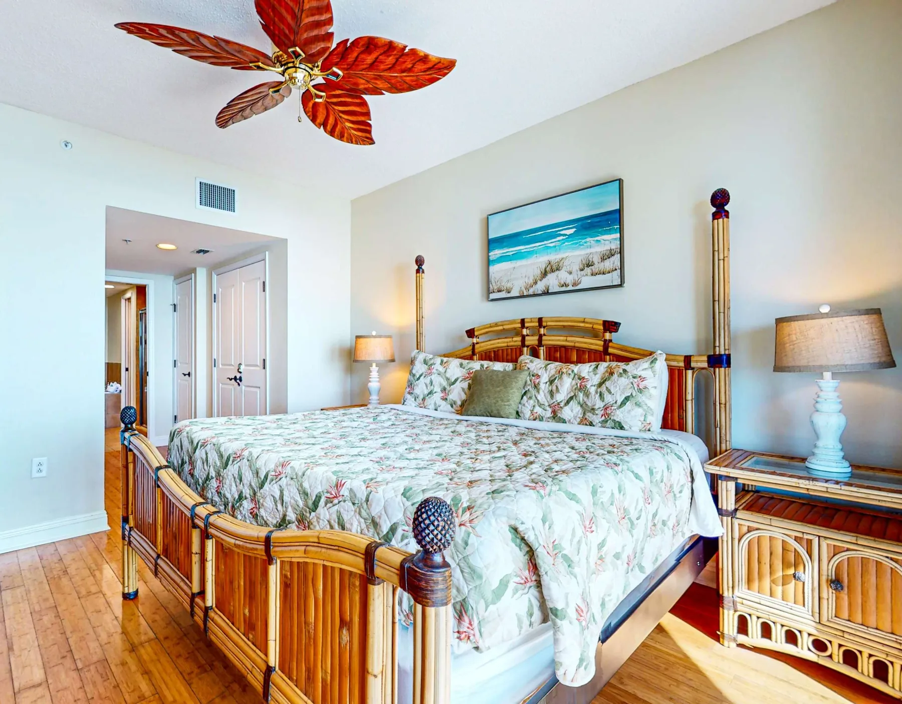 Un dormitorio con una cama de madera, ropa de cama floral y una imagen enmarcada de la playa.