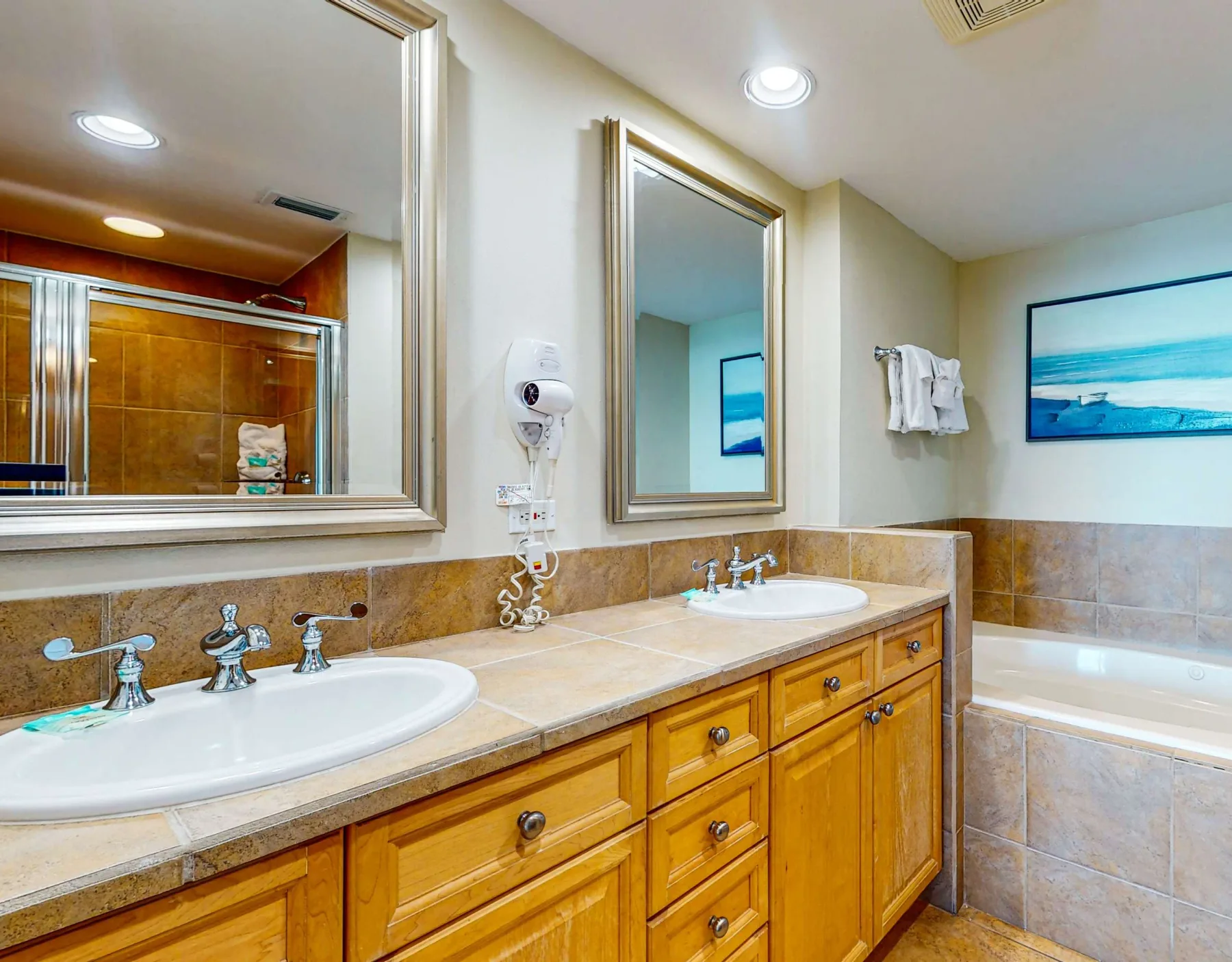Un baño con un tocador largo de dos lavabos y una bañera.