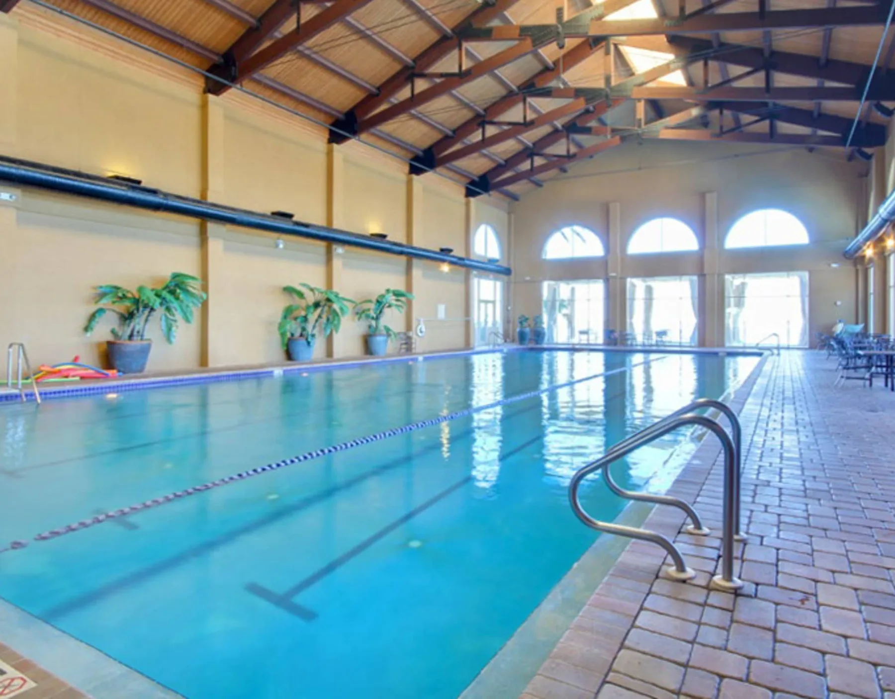 Zona común: Una piscina cubierta con grandes ventanas arqueadas y un borde embaldosado.