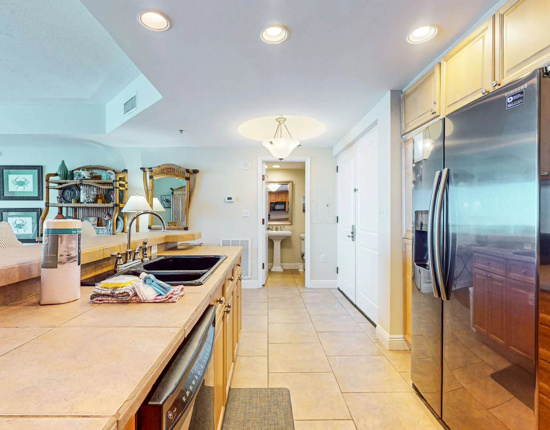 Una cocina luminosa con una encimera larga, una placa de cocina y un refrigerador de acero inoxidable.