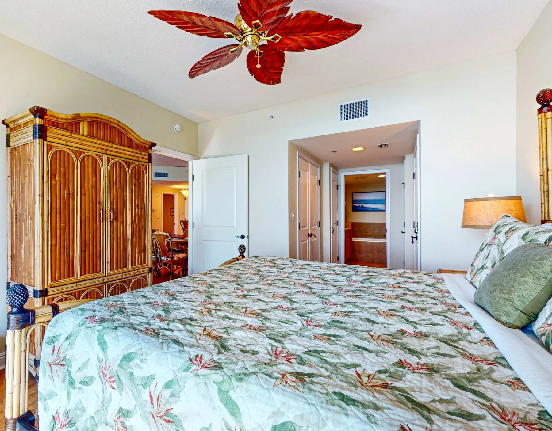 Un dormitorio con una colcha floral y un armario alto de madera.
