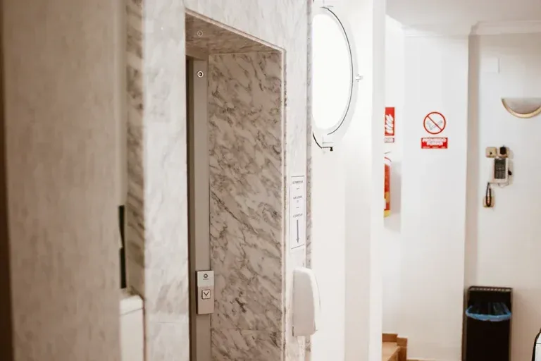 Representative hotel space: A hotel bathroom entrance with a wall-mounted mirror and waste bin.