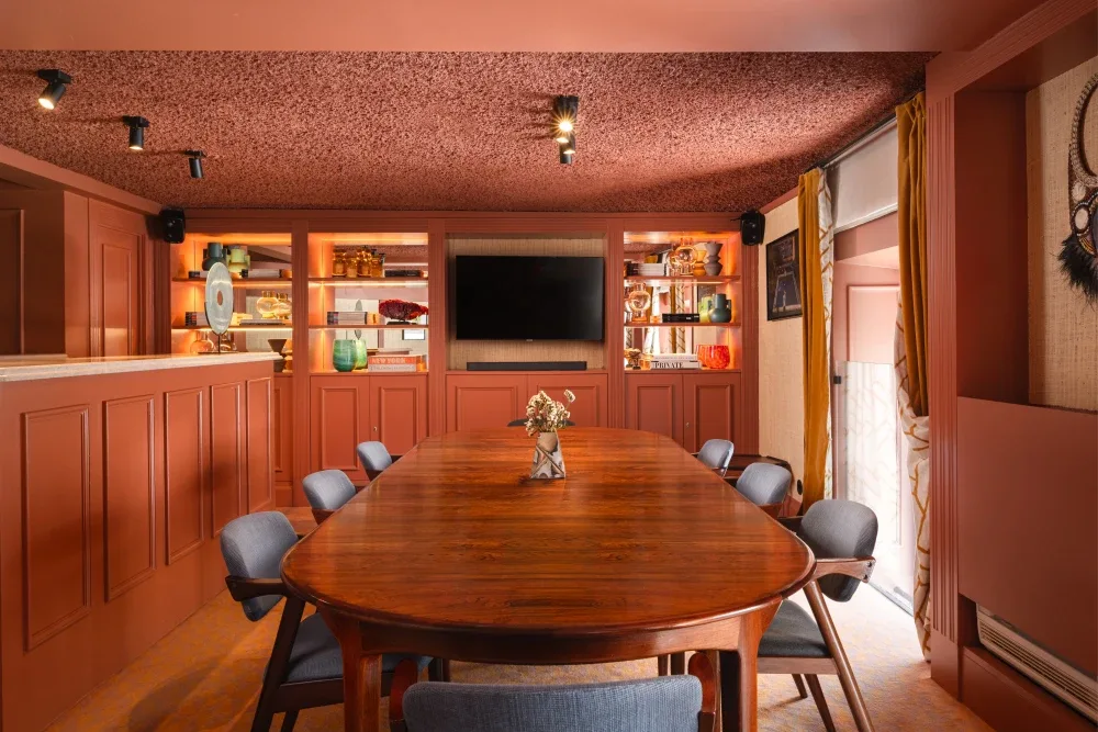 Espacio representativo del hotel: Sala de reuniones revestida de madera, con una mesa larga y estantes de exhibición.