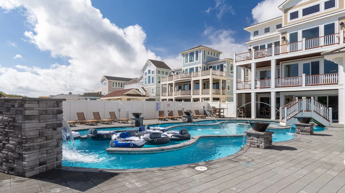 An outdoor swimming pool sits beside a large multi-story building.