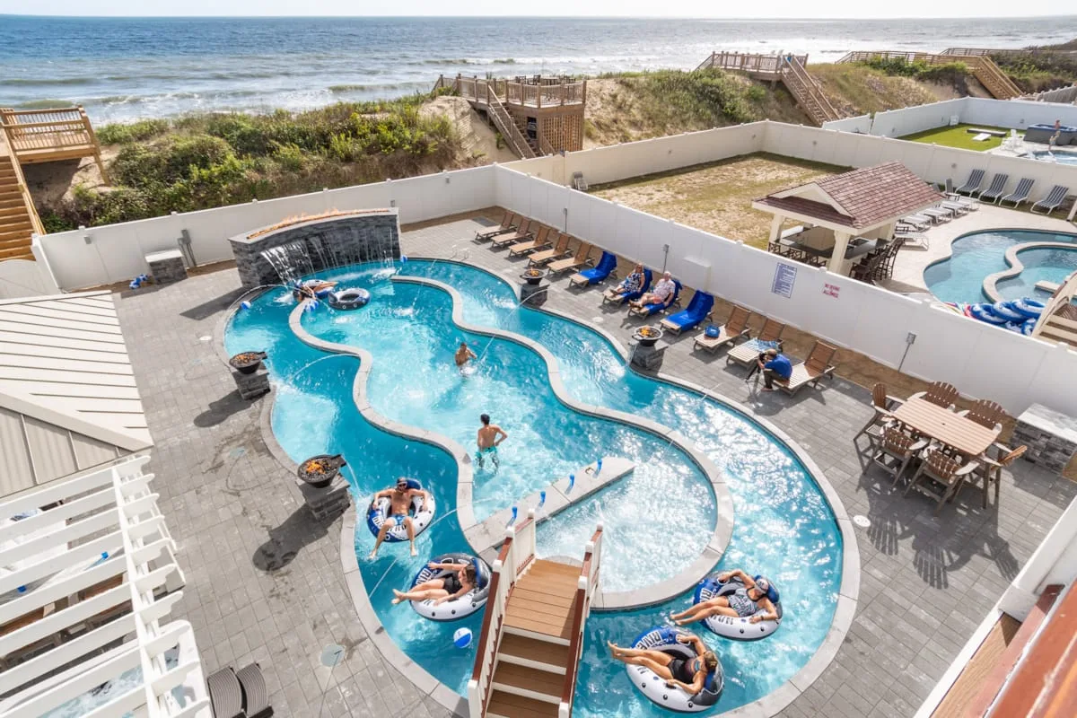 Una piscina exterior serpenteante está rodeada de asientos en una terraza soleada.