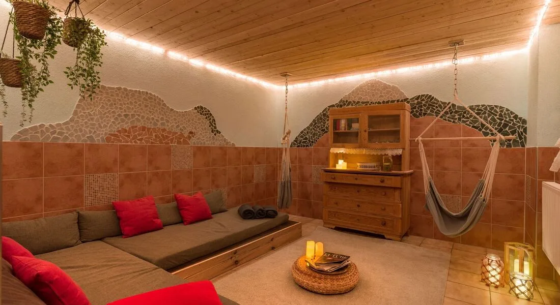 Espacio representativo del hotel: Un salón con asientos bajos, una hamaca e iluminación cálida.
