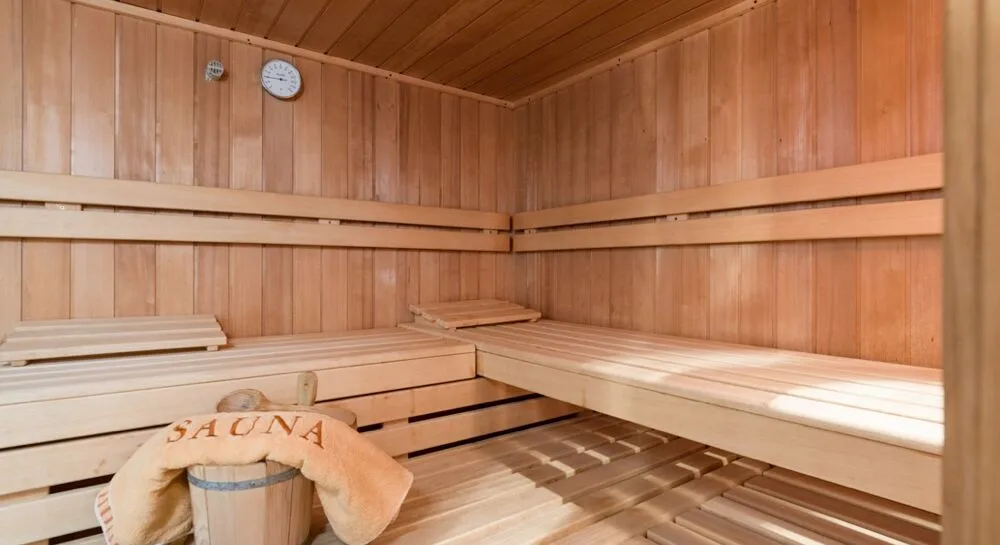 Espacio representativo del hotel: Una sauna revestida de madera con bancos escalonados y un reloj redondo en la pared.