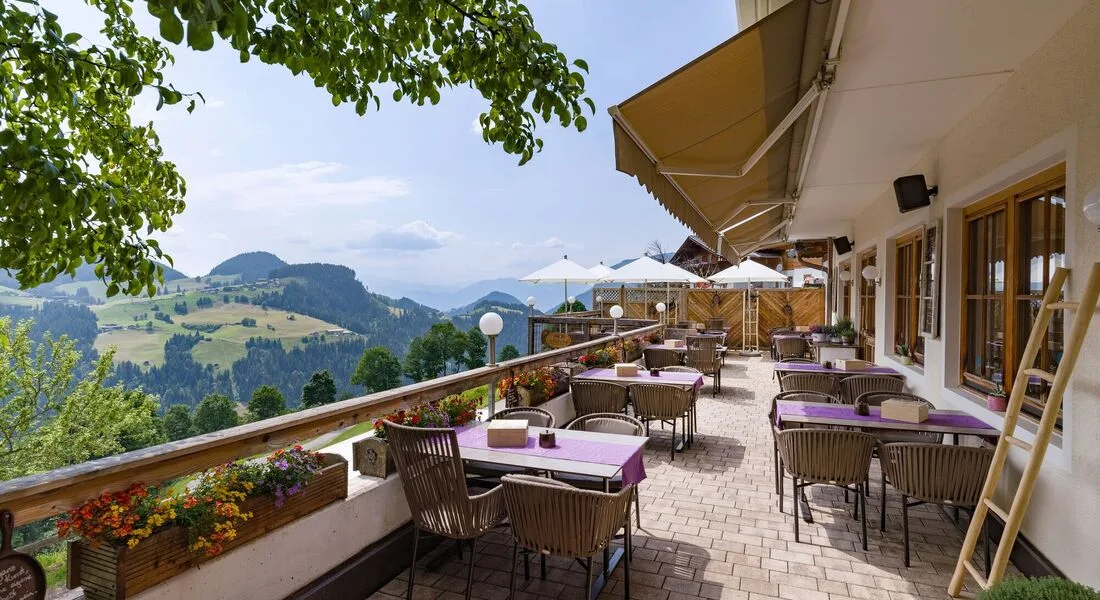 Espacio representativo del hotel: Terraza exterior con mesas y vistas a las montañas.