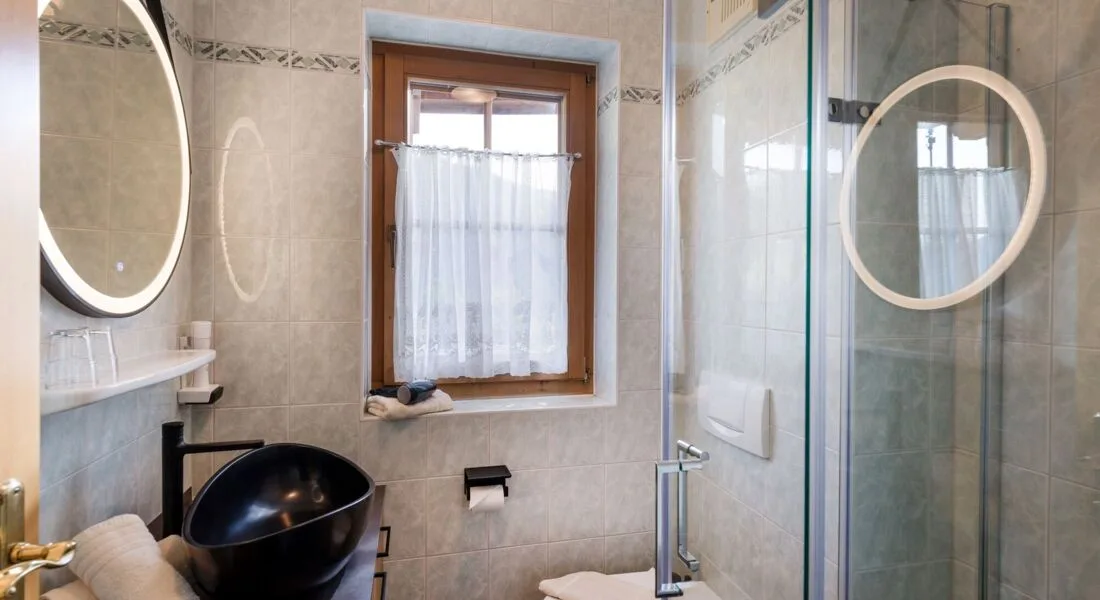 Espacio representativo del hotel: Un baño alicatado con ventana, lavabo y ducha.
