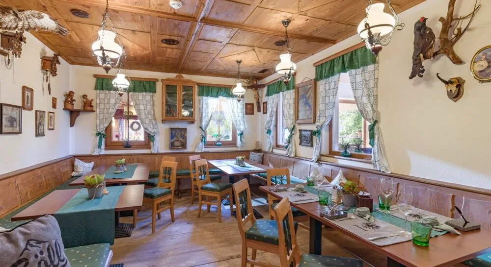 Espacio representativo del hotel: Un comedor con mesas y sillas de madera junto a ventanas con cortinas.