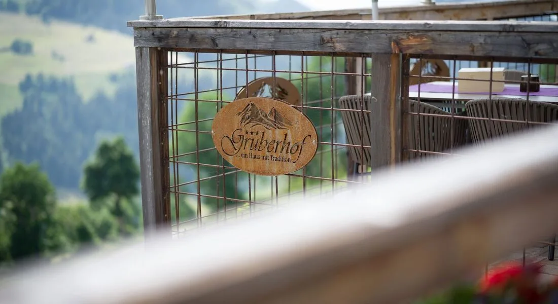 Espacio representativo del hotel: Una barandilla de madera al aire libre da a un paisaje montañoso verde.