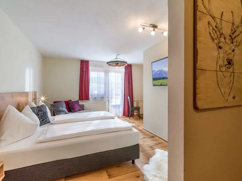 Espacio representativo del hotel: Un dormitorio con dos camas, cortinas rojas y una ventana.