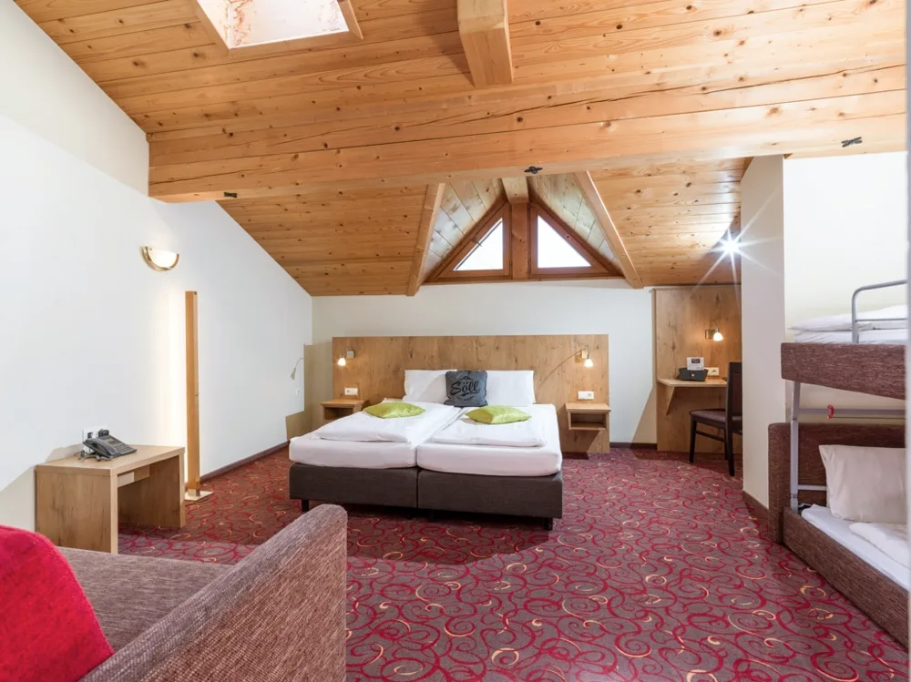 Espacio representativo del hotel: Un dormitorio de hotel con dos camas bajo un techo de madera inclinado.
