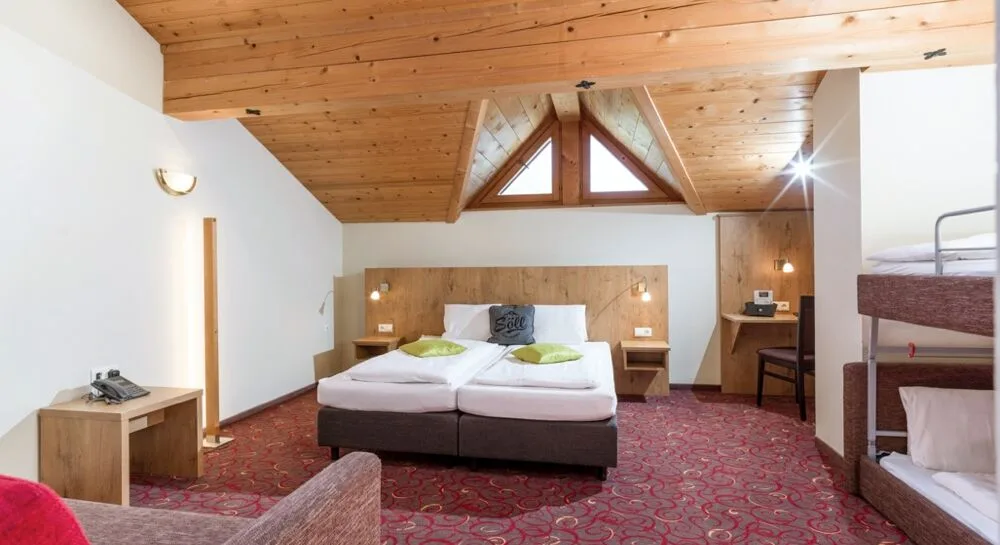 Espacio representativo del hotel: Un dormitorio con dos camas bajo un techo inclinado de madera.