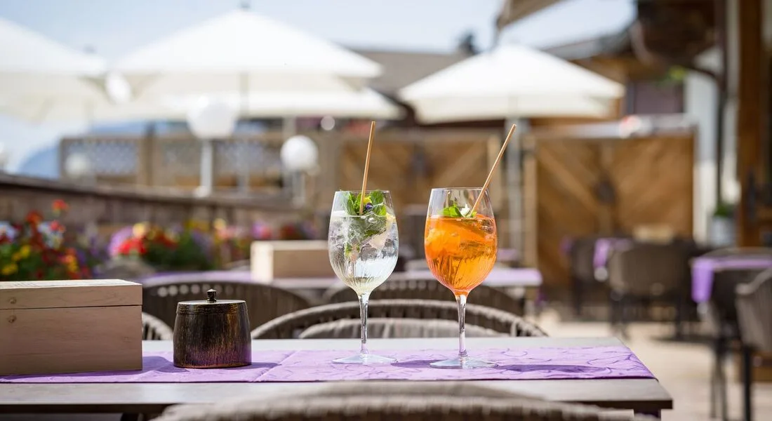 Espacio representativo del hotel: Mesa en un patio al aire libre con dos bebidas coloridas bajo sombrillas blancas.