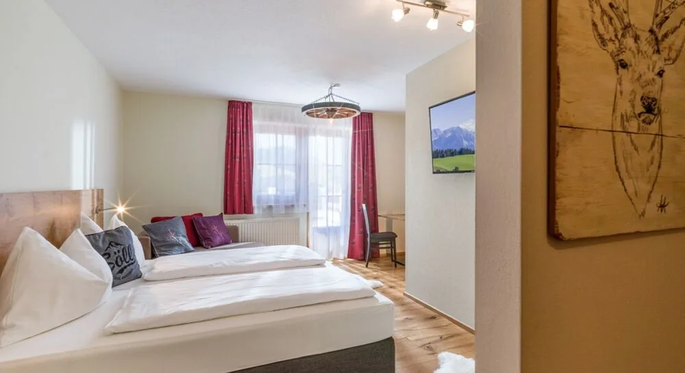 Espacio representativo del hotel: Un dormitorio con una cama grande, cortinas rojas y un televisor.