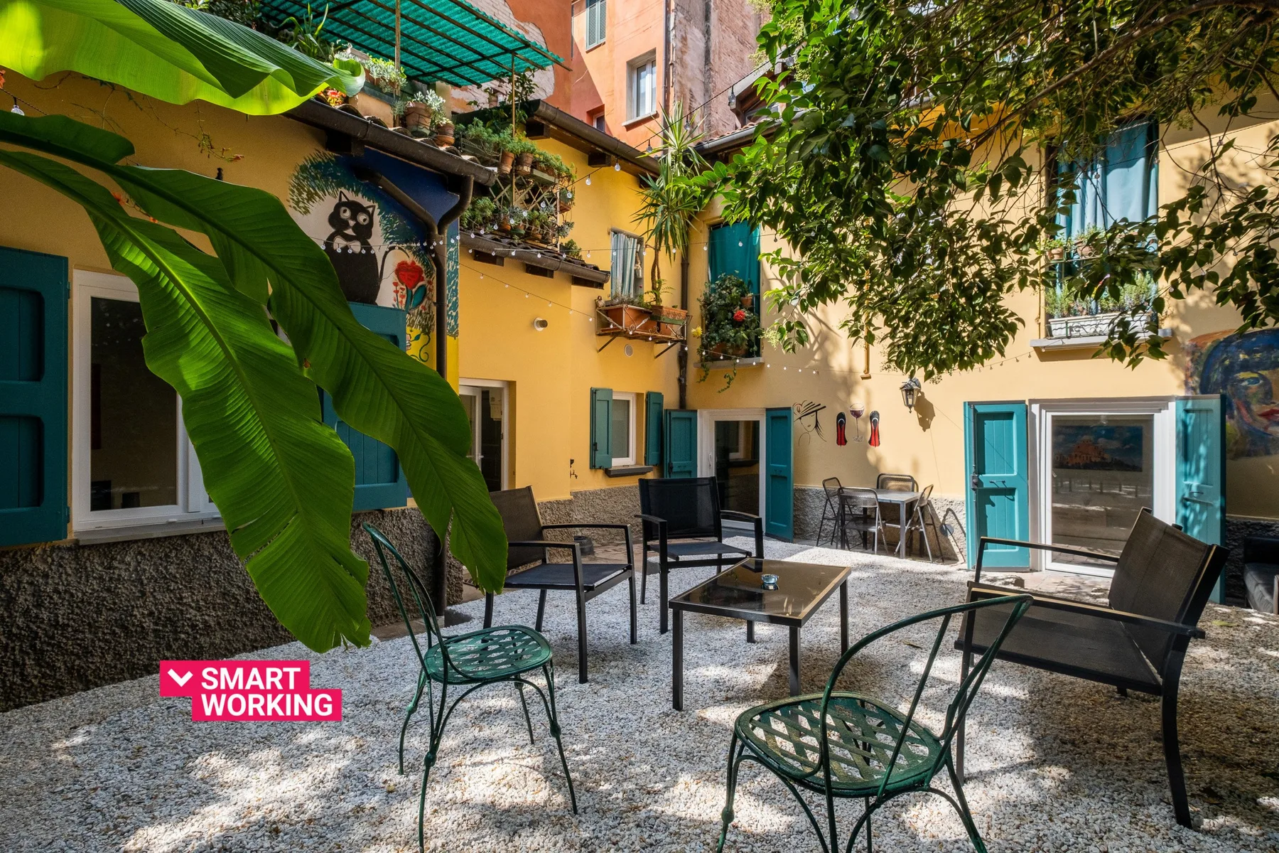 Un patio interior con asientos al aire libre y plantas frondosas.