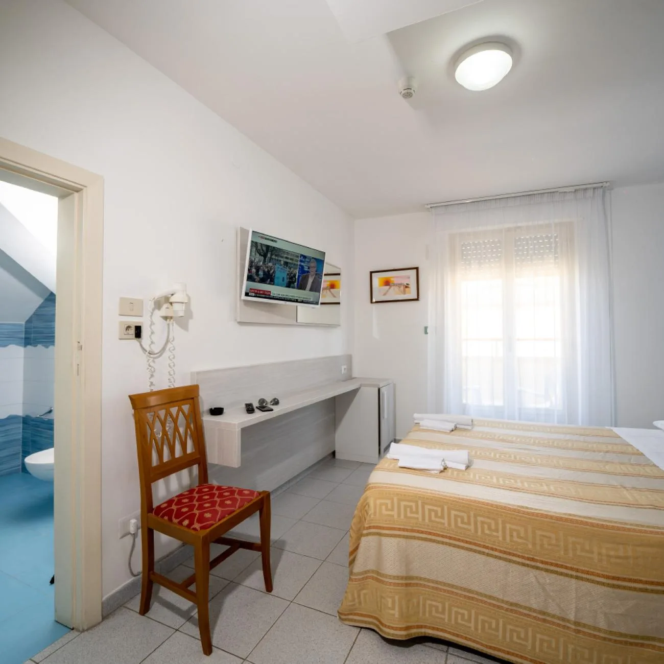 Espacio representativo del hotel: Dormitorio de hotel con camas, una silla y un televisor.