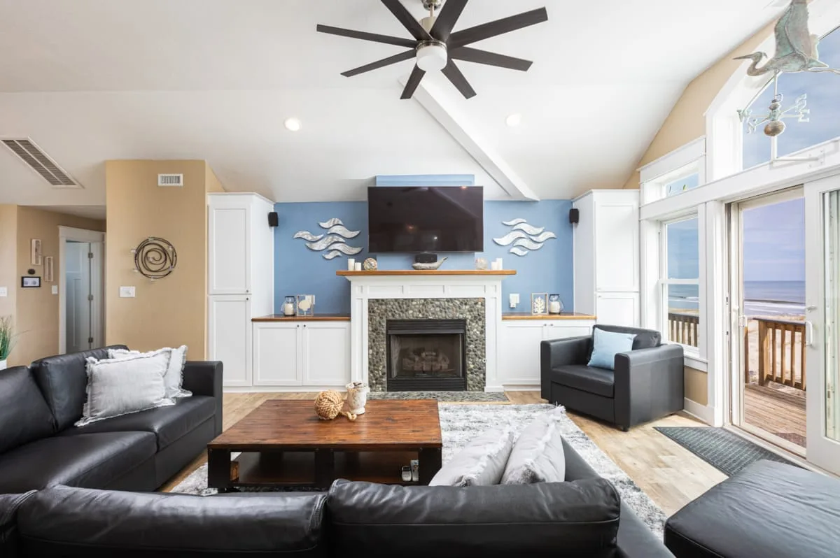 A living room with seating around a coffee table and a fireplace beneath a television.