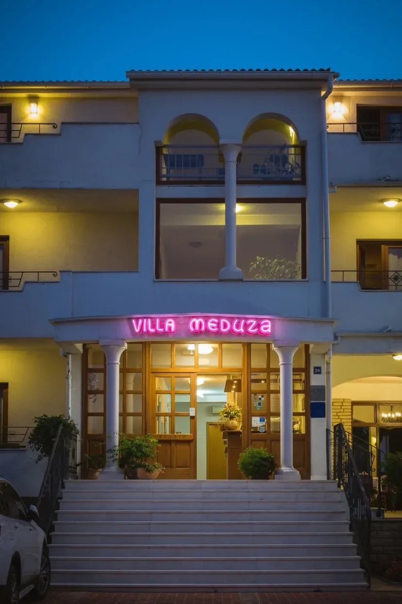 Representative hotel space: A hotel entrance with broad steps and a lit sign above the doorway.