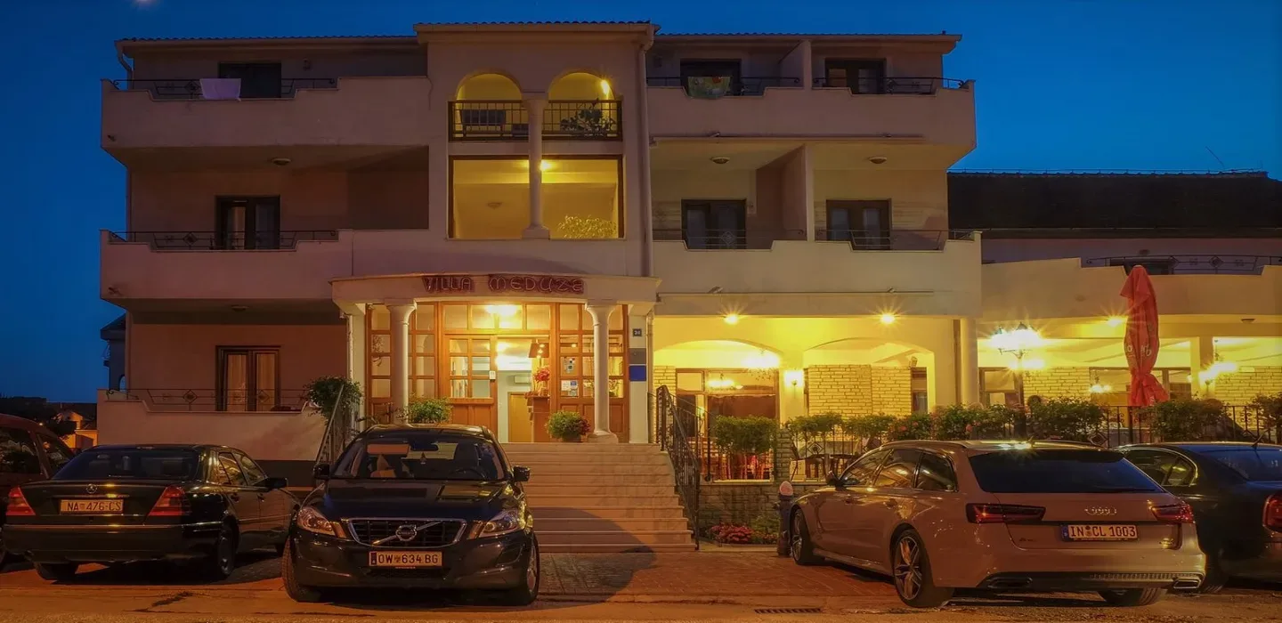 Representative hotel space: A multi-story building with a brightly lit ground-floor entrance at dusk.