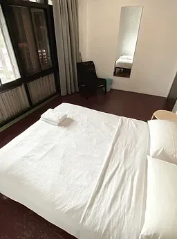 Representative hotel space: A bedroom with a white bed and a chair beside the window.