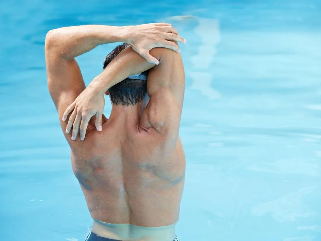Representative hotel space: A person stretches their arms beside a swimming pool.