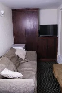 Espacio representativo del hotel: Una sala de estar con asientos, un televisor y un armario oscuro.