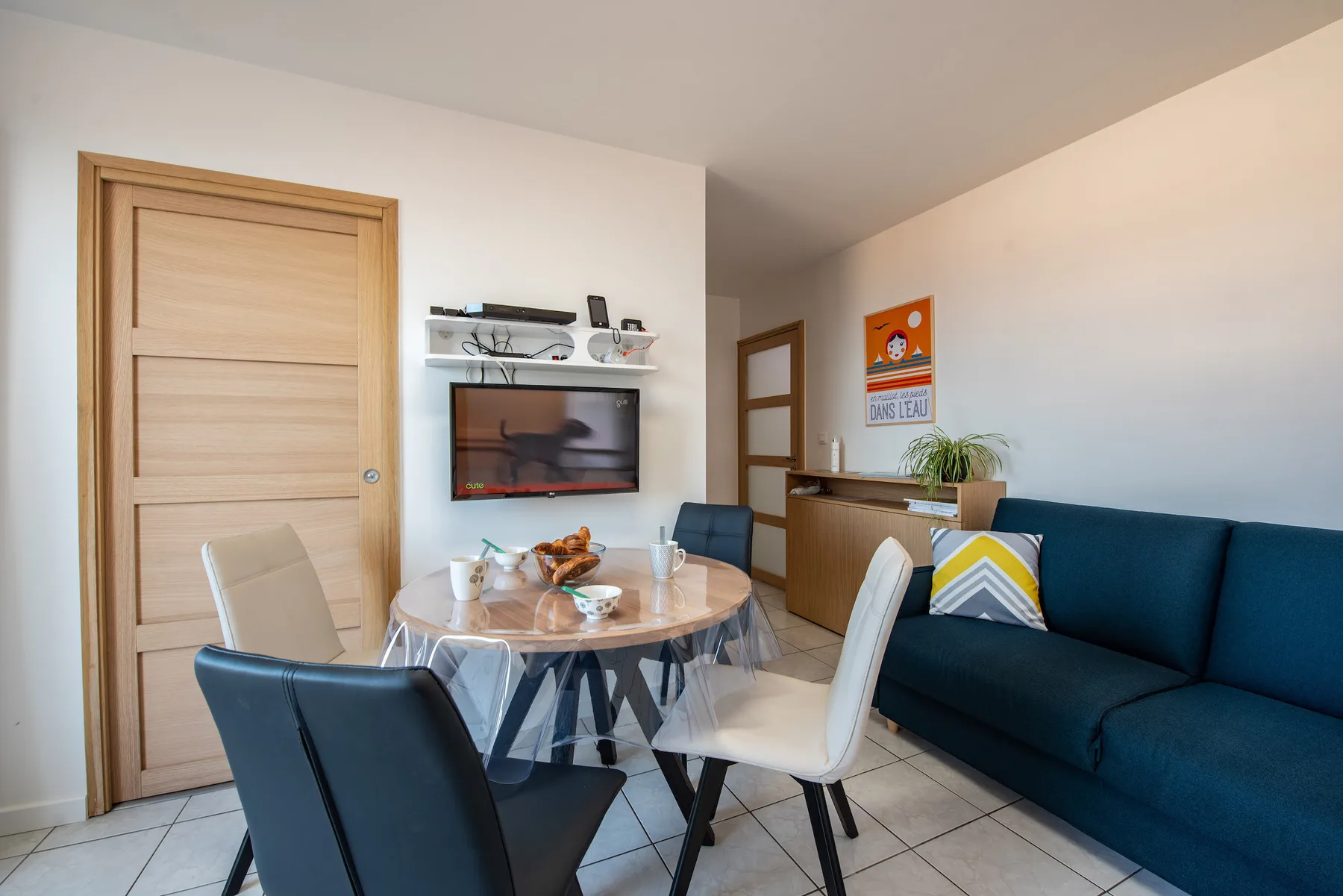 A dining and living area with a round table and a blue sofa.