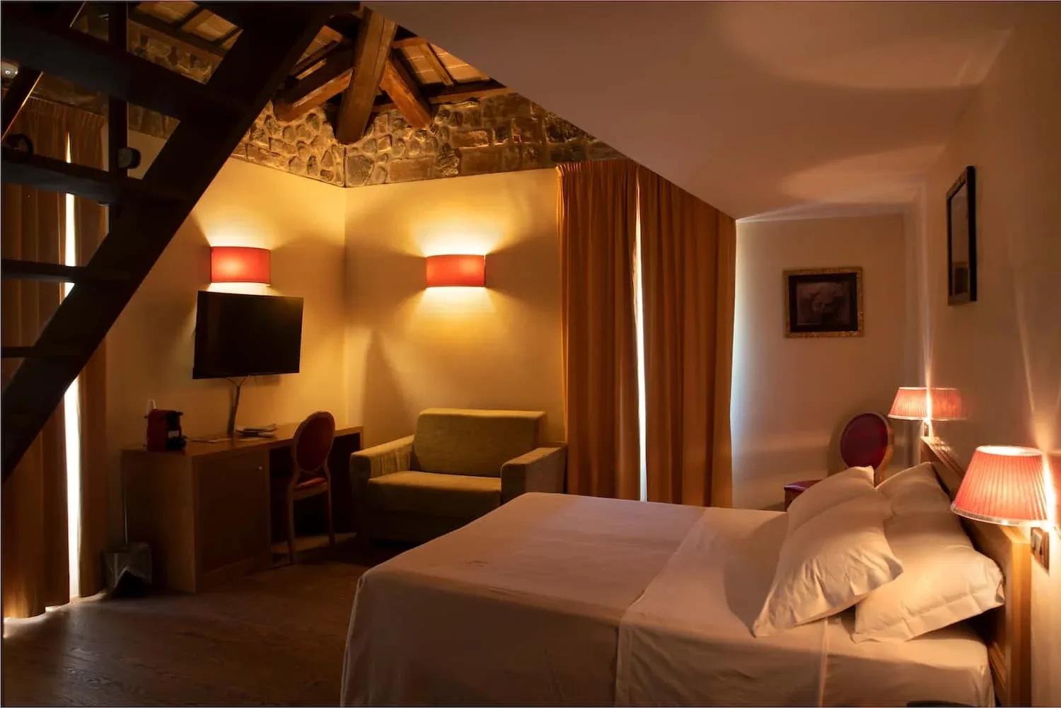Representative hotel space: A warmly lit hotel bedroom with a bed, seating area, and exposed wooden beams.