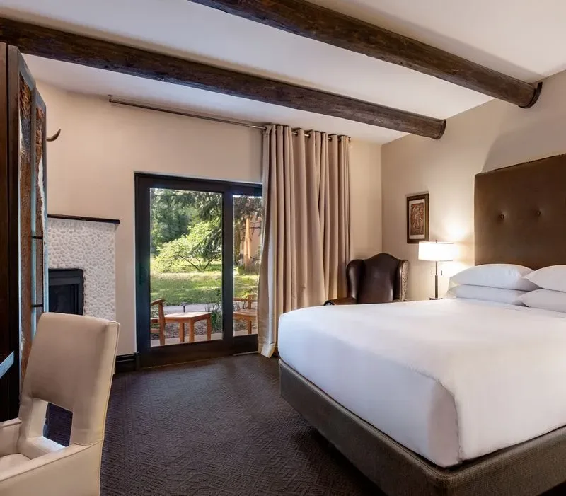 Representative hotel space: A bedroom with a large bed and glass doors opening onto greenery.