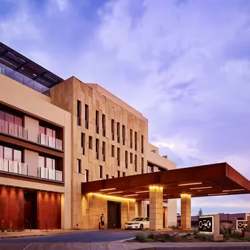 Representative hotel space: A modern hotel entrance with a covered vehicle drop-off beneath a cloudy sky.