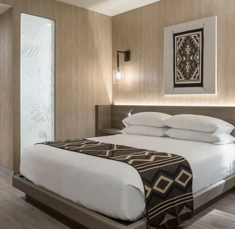 Representative hotel space: A bedroom with a neatly made bed and geometric wall art.