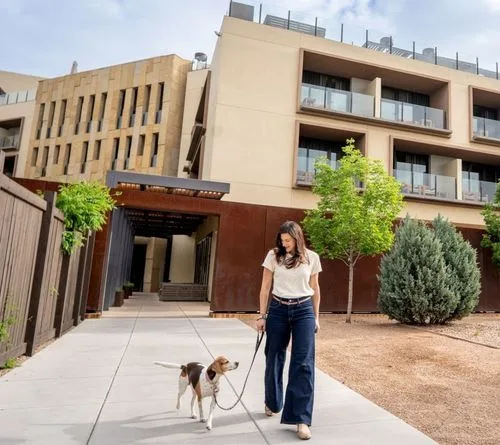Representative hotel space: A modern building entrance opens onto a paved walkway beside landscaped grounds.
