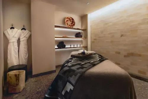 Representative hotel space: A spa treatment room with a massage table and robes hanging on the wall.