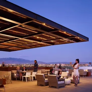 Representative hotel space: An outdoor rooftop dining and seating area sits beneath a broad lit canopy.