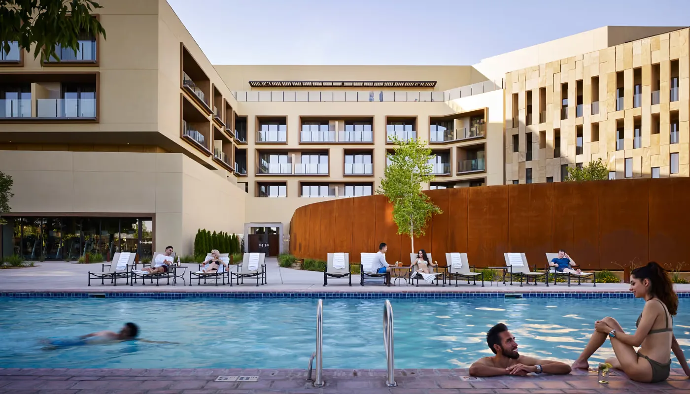 Representative hotel space: An outdoor pool beside lounge seating and modern hotel buildings.