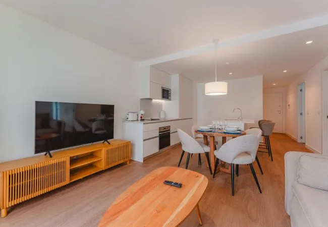 An open-plan living and dining area with a television and a set dining table.