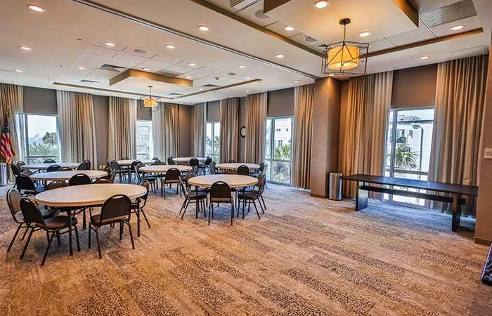 Espacio representativo del hotel: Una sala de reuniones con mesas redondas, asientos y ventanas con cortinas.