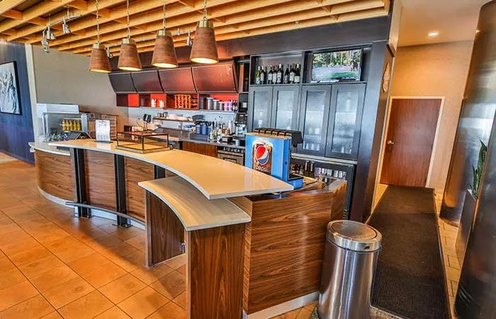 Espacio representativo del hotel: Un bar de hotel tiene una barra curva con frente de madera y refrigeradores de bebidas.