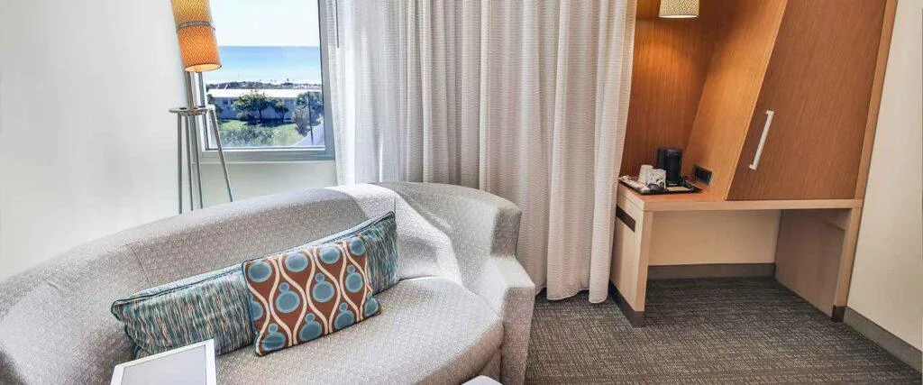 Espacio representativo del hotel: Zona de estar con un sofá curvo junto a una ventana y un escritorio.